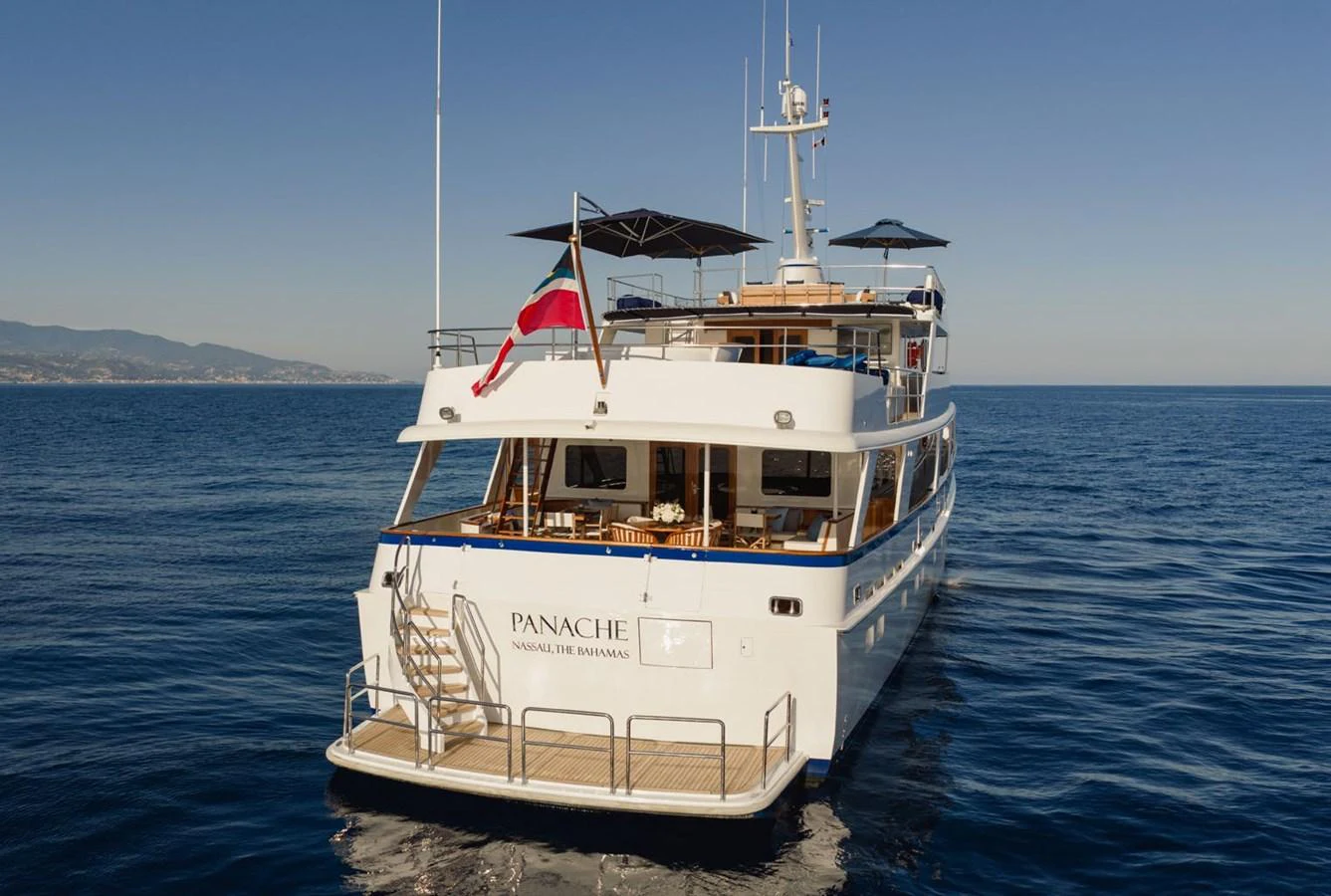 A luxurious yacht is anchored on calm waters with a clear view of its spacious aft deck and elegant design. aboard PANACHE Yacht for Sale