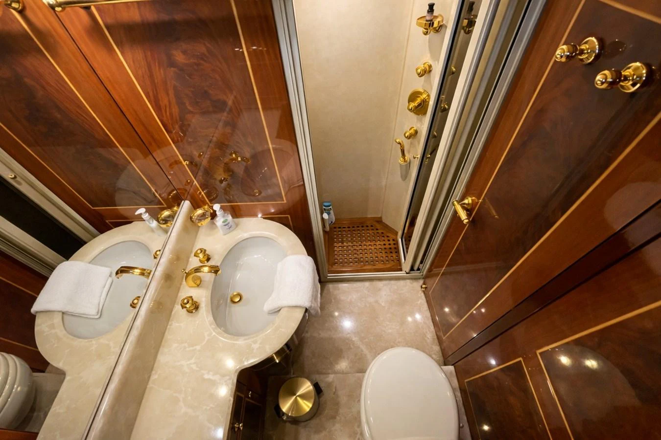 The yacht's bathroom features elegant wood paneling, a marble countertop, and gold fixtures. aboard ANGELINA Yacht for Sale