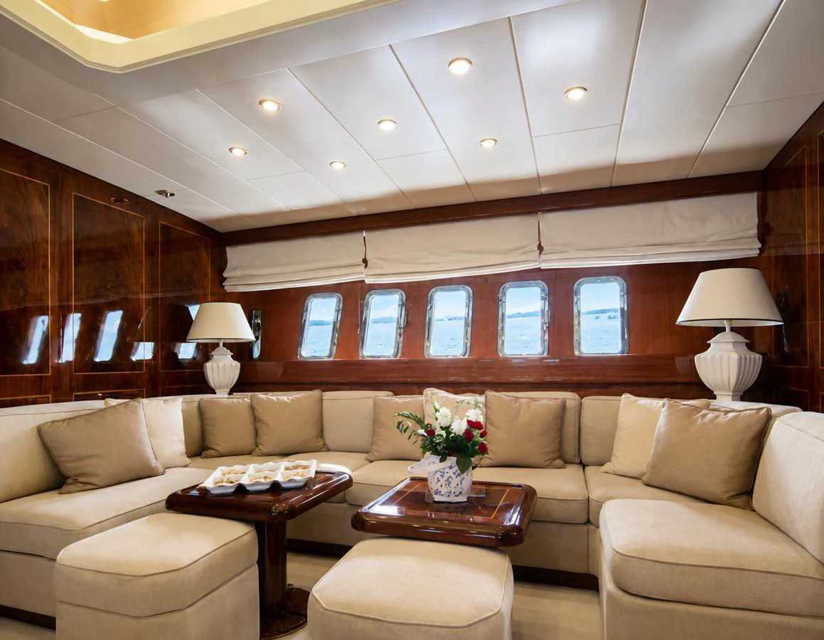 The salon features plush seating, elegant wood paneling, and ample natural light through large windows. aboard ANGELINA Yacht for Sale
