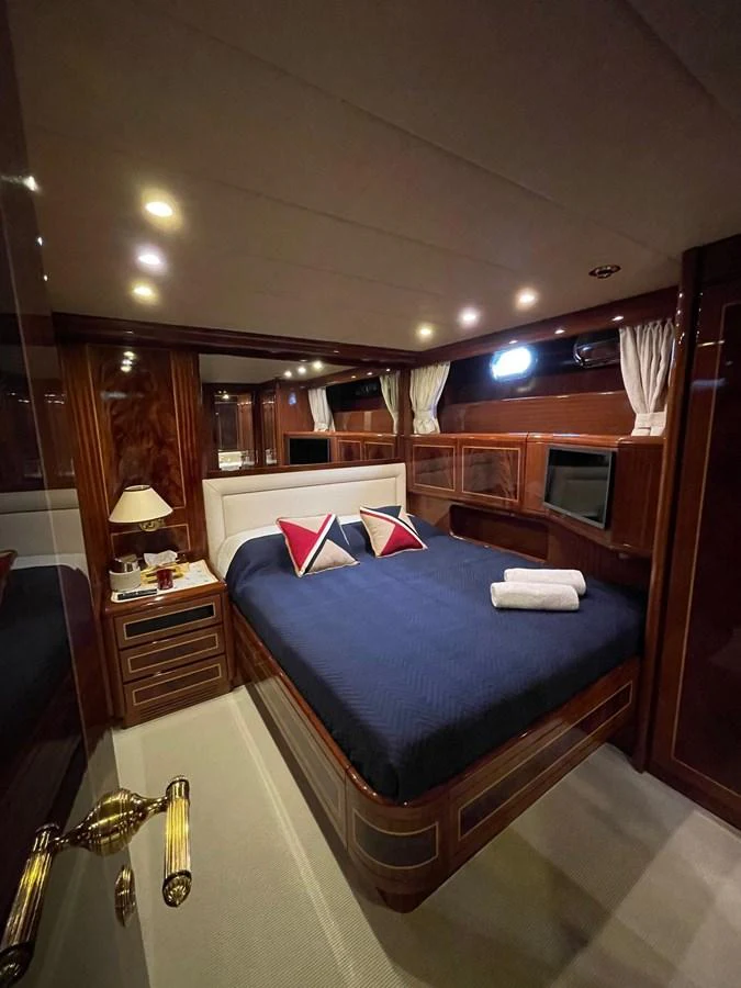 The stateroom features a plush bed with elegant wood paneling and ambient lighting. aboard ANGELINA Yacht for Sale