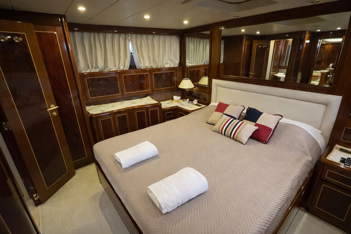 The stateroom features a luxurious bed with elegant wood paneling and ample lighting. aboard ANGELINA Yacht for Sale