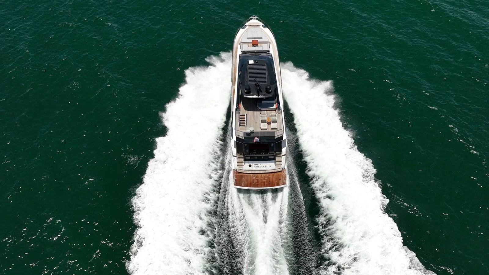 A sleek yacht cruises through the open water, leaving a trail of white wake behind. aboard HOTEL COLLECTION Yacht for Sale