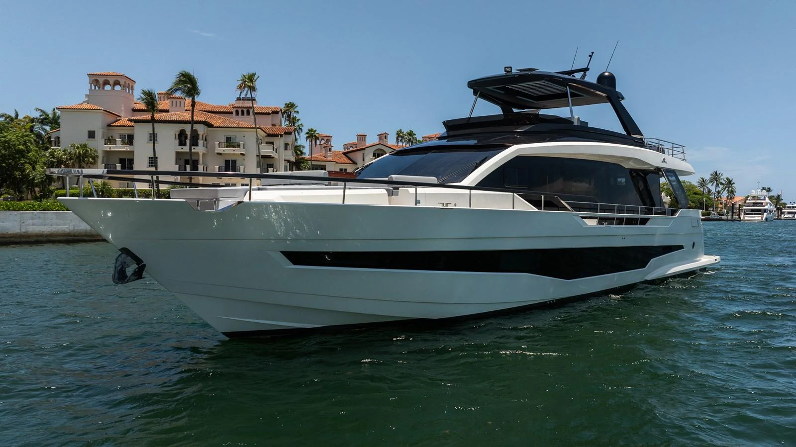 A sleek and modern yacht glides gracefully on the water with a luxurious backdrop of waterfront villas. aboard HOTEL COLLECTION Yacht for Sale