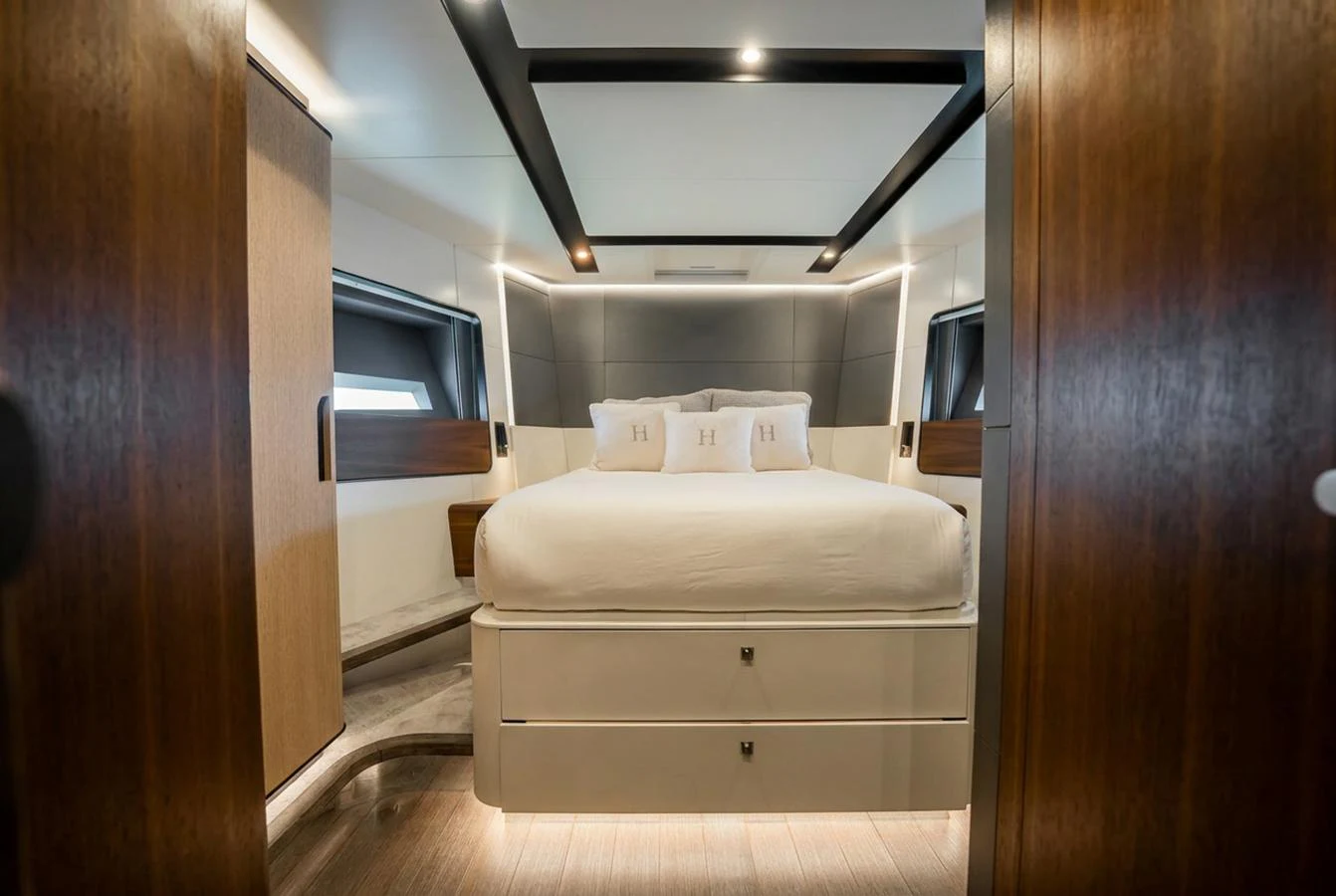 The master stateroom features a luxurious bed with elegant wood finishes and modern lighting. aboard HOTEL COLLECTION Yacht for Sale