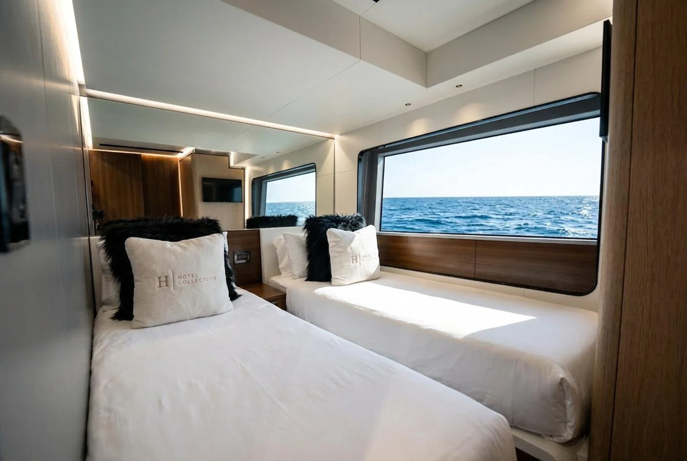 The guest stateroom features twin beds with a large window offering a stunning ocean view. aboard HOTEL COLLECTION Yacht for Sale