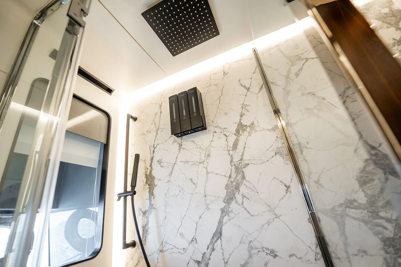 The yacht's bathroom features a luxurious marble wall and a modern shower setup. aboard HOTEL COLLECTION Yacht for Sale