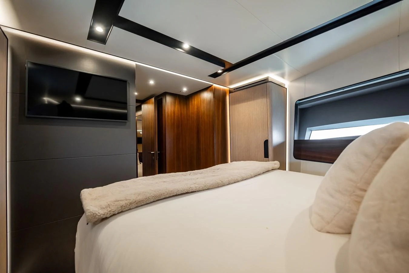 The stateroom features a plush bed, modern lighting, and a sleek television for ultimate relaxation. aboard HOTEL COLLECTION Yacht for Sale