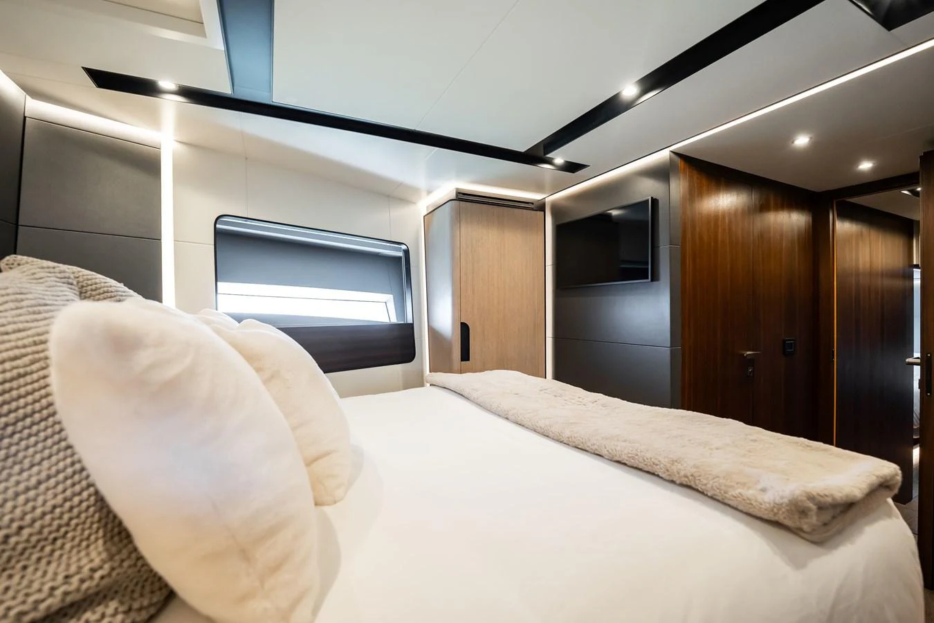 This luxurious stateroom features a plush bed with elegant bedding and modern wood paneling. aboard HOTEL COLLECTION Yacht for Sale