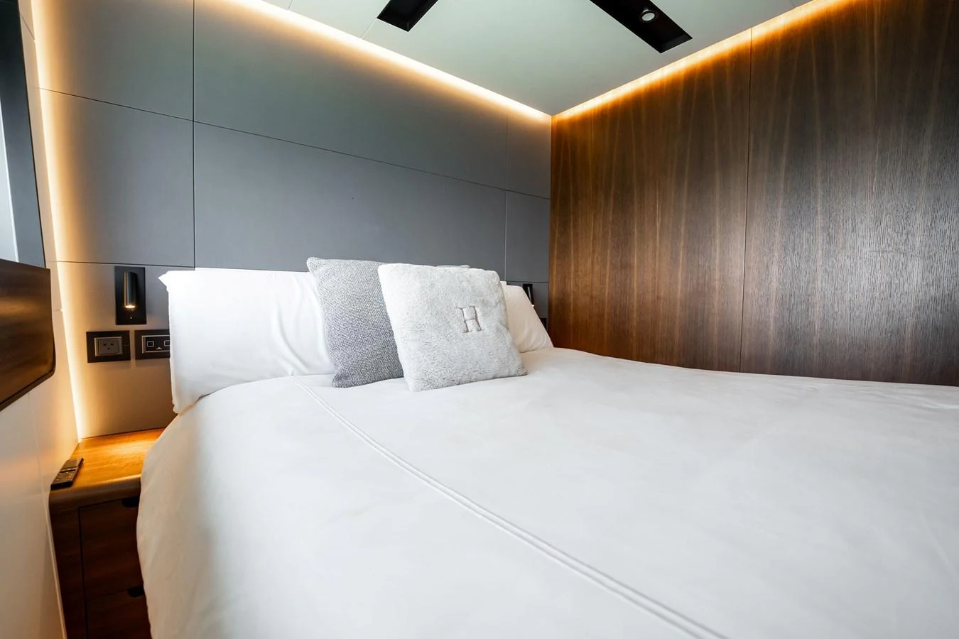 A luxurious stateroom featuring a comfortable bed with plush pillows and modern lighting. aboard HOTEL COLLECTION Yacht for Sale