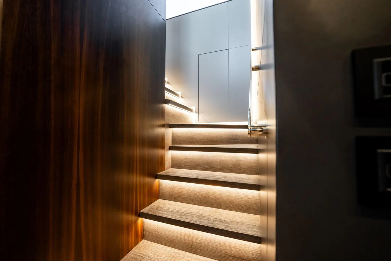 A modern, well-lit staircase with wooden steps and sleek design elements. aboard HOTEL COLLECTION Yacht for Sale