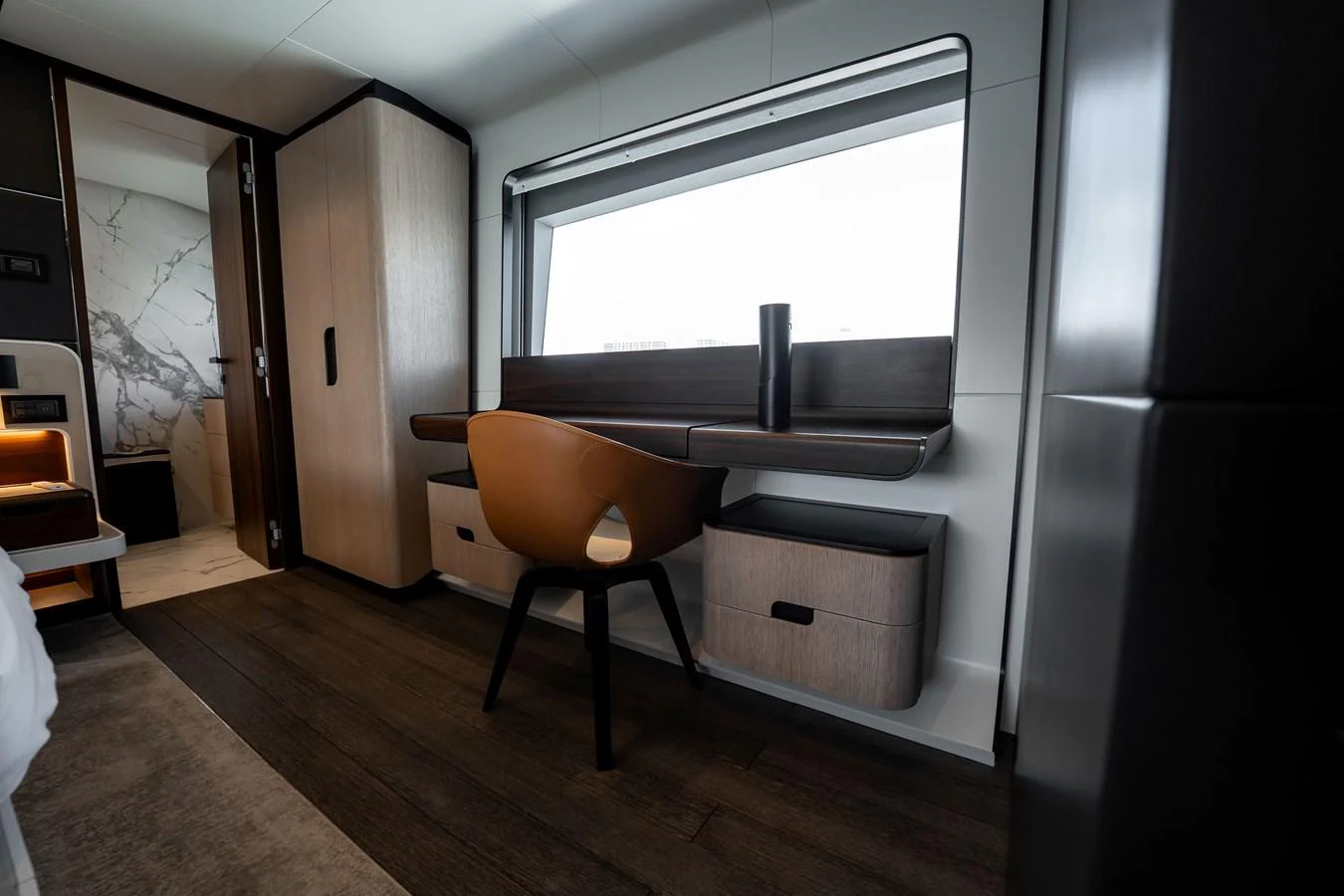 A modern stateroom with a sleek desk and comfortable chair, featuring elegant wood finishes and a large window. aboard HOTEL COLLECTION Yacht for Sale
