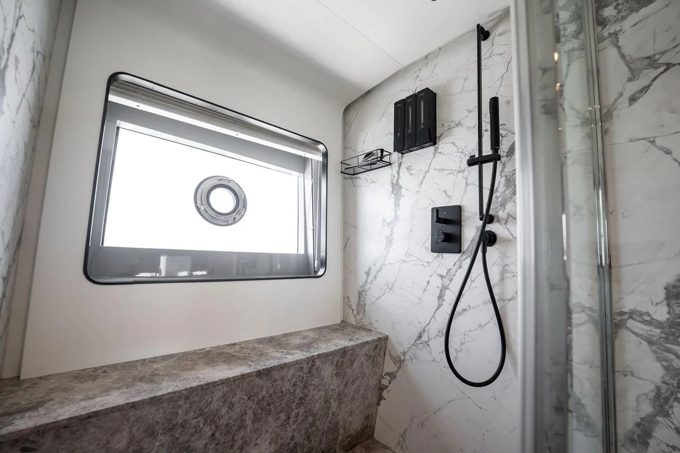 The yacht's bathroom features a sleek, modern design with marble accents and a large window. aboard HOTEL COLLECTION Yacht for Sale