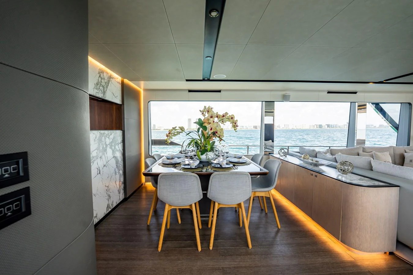The yacht's dining area features a modern table set with elegant decor, surrounded by large windows offering stunning sea views. aboard HOTEL COLLECTION Yacht for Sale