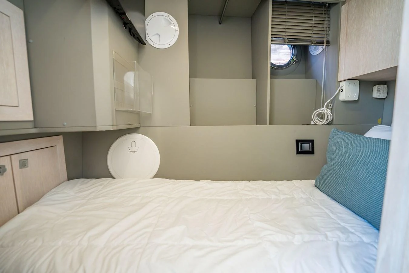 A cozy cabin with a single bed and a small porthole window. aboard HOTEL COLLECTION Yacht for Sale