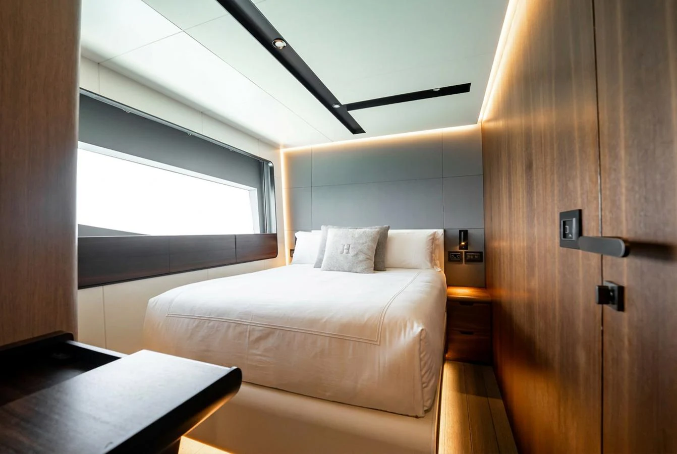 A luxurious stateroom featuring a large bed with modern design elements and ample natural light. aboard HOTEL COLLECTION Yacht for Sale
