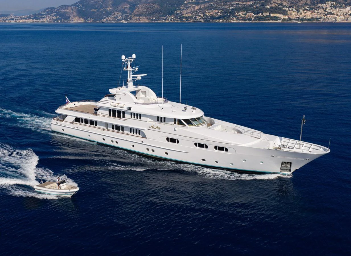 A luxurious white yacht cruises through clear blue waters, accompanied by a sleek tender. aboard MY LADY Yacht for Sale