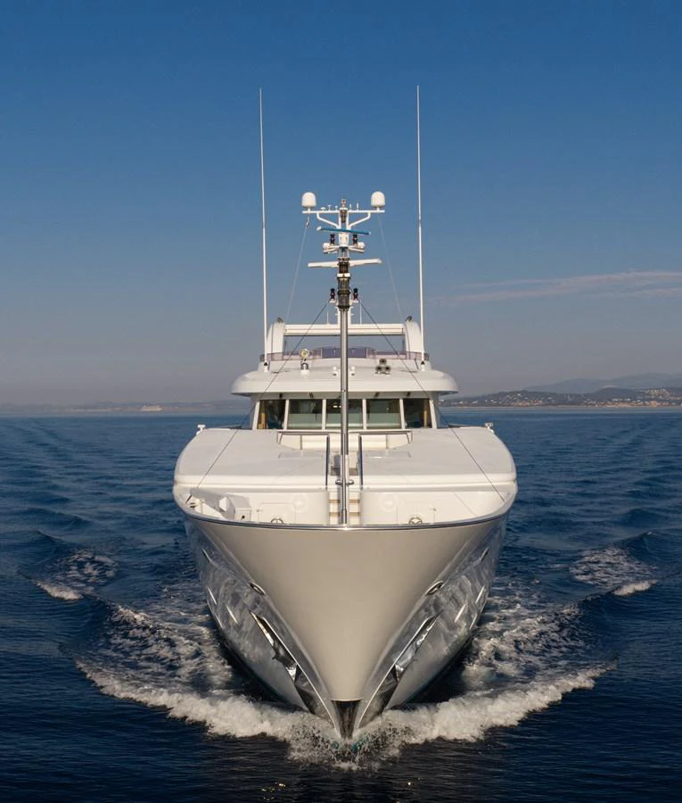 A sleek yacht cruises forward on calm waters under a clear blue sky. aboard MY LADY Yacht for Sale