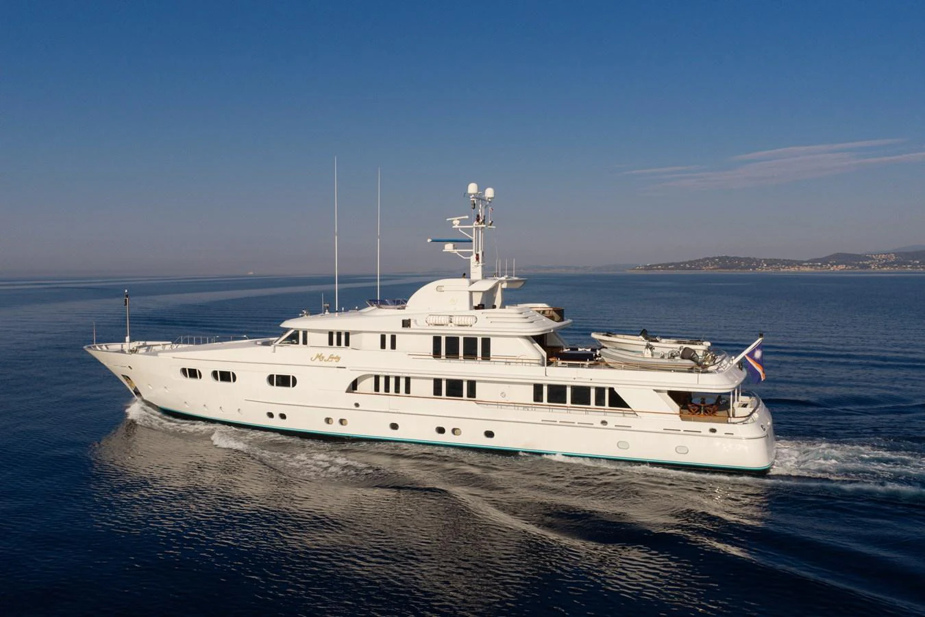 A luxurious yacht cruises smoothly on calm waters under a clear blue sky. aboard MY LADY Yacht for Sale