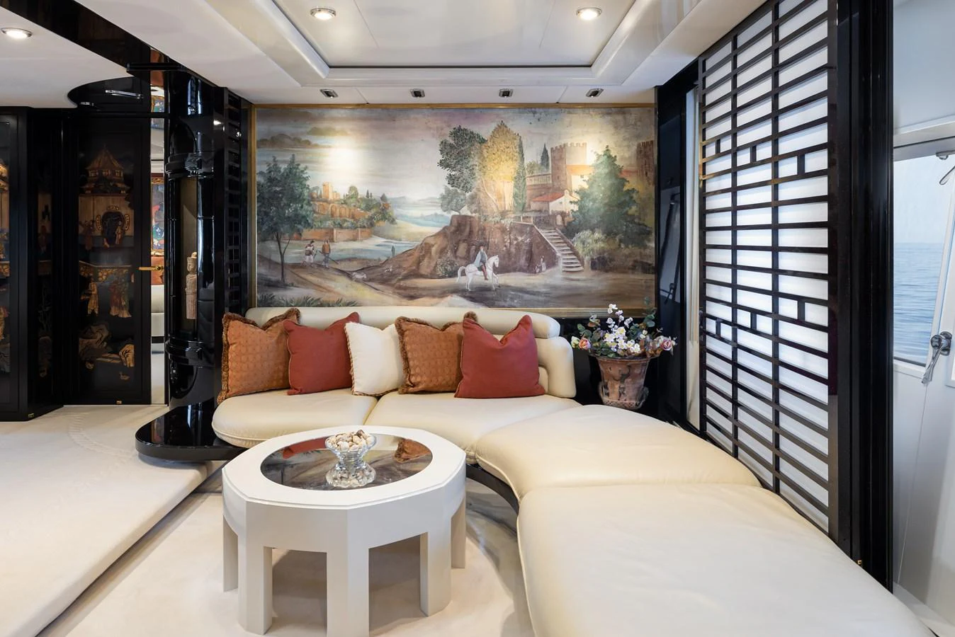 The yacht's interior features a luxurious lounge area with a curved white sofa, accented by a scenic mural and elegant decor. aboard MY LADY Yacht for Sale