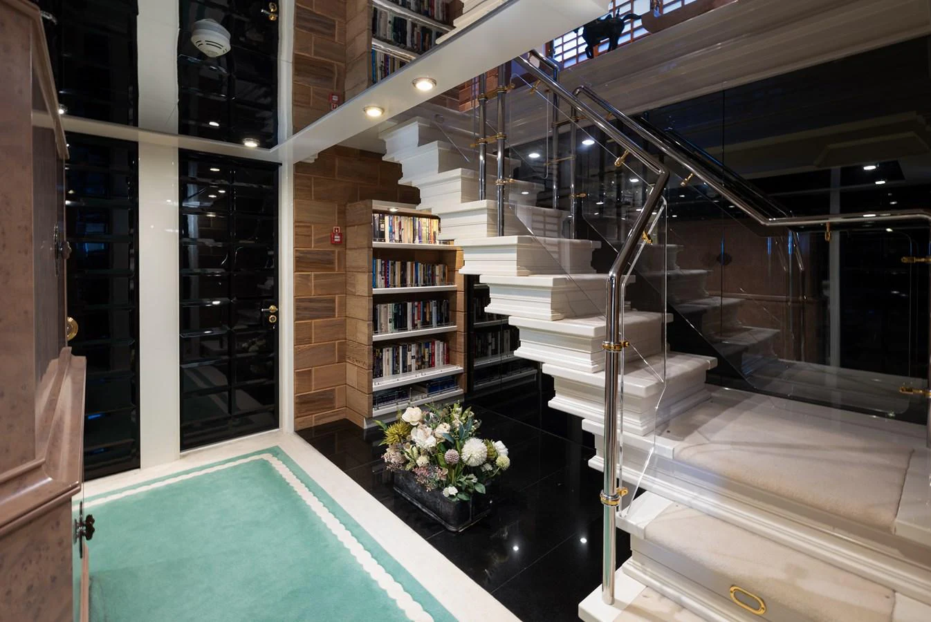 A sophisticated interior space featuring a modern staircase and a well-stocked bookshelf. aboard MY LADY Yacht for Sale