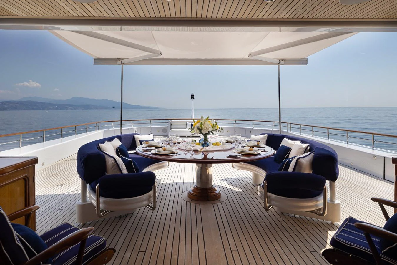 The aft deck features an elegant dining area with a round table and comfortable seating, perfect for enjoying meals with a sea view. aboard MY LADY Yacht for Sale