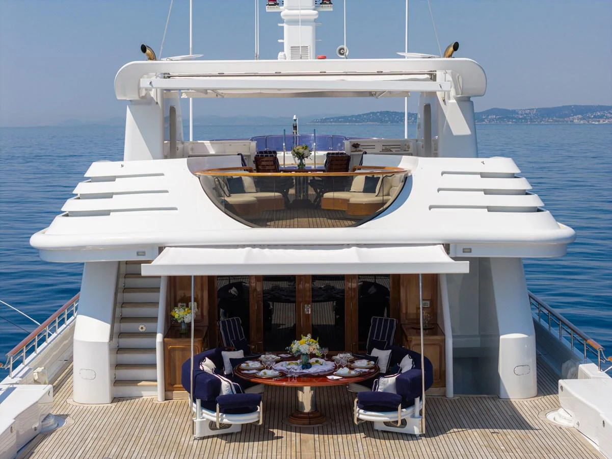 The yacht's aft deck features an elegant dining area with a view of the serene sea. aboard MY LADY Yacht for Sale