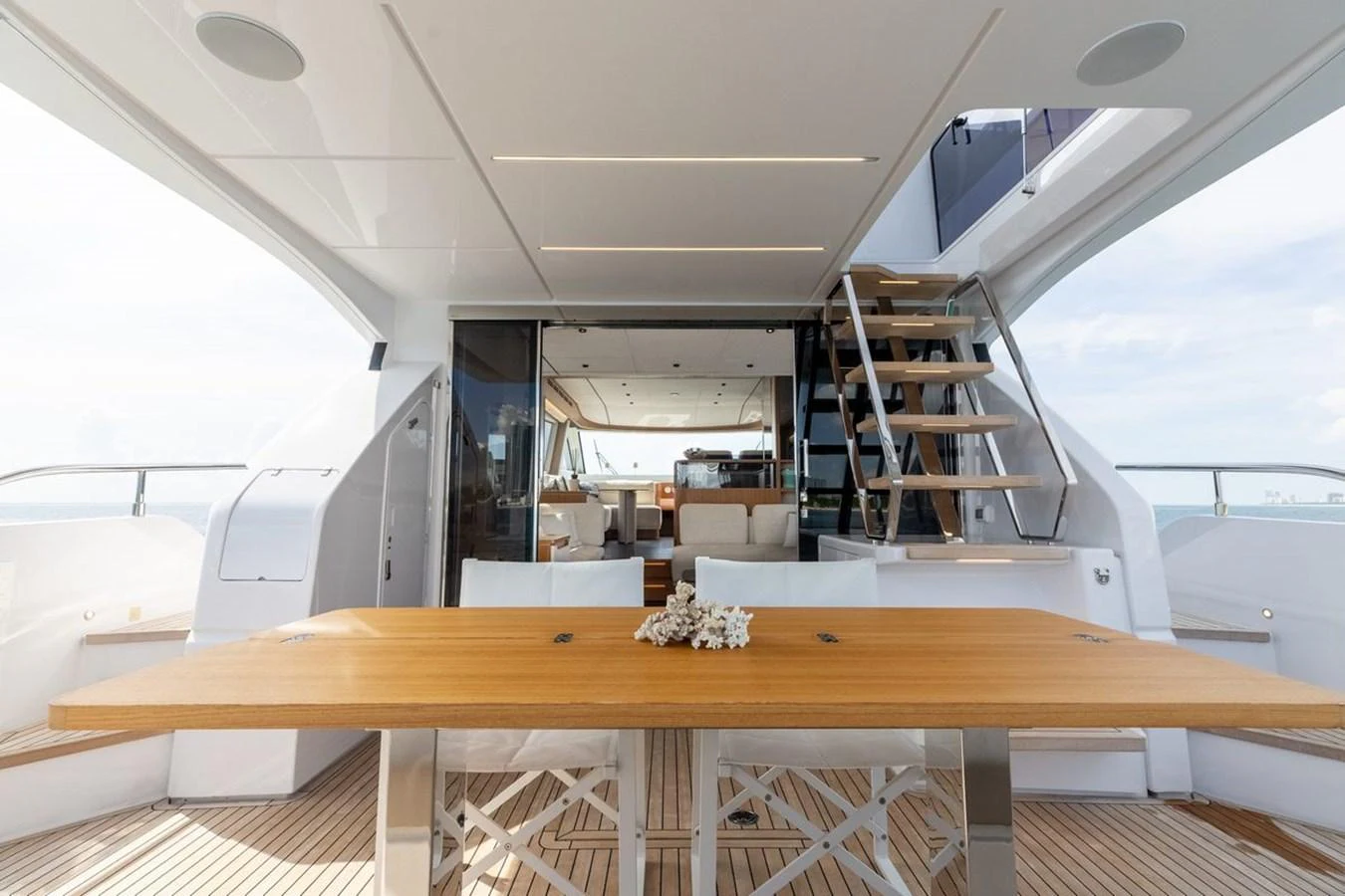 The aft deck features a stylish dining area with a wooden table and comfortable seating, perfect for alfresco meals. aboard 2025 FERRETTI 670 KATRIN I Yacht for Sale
