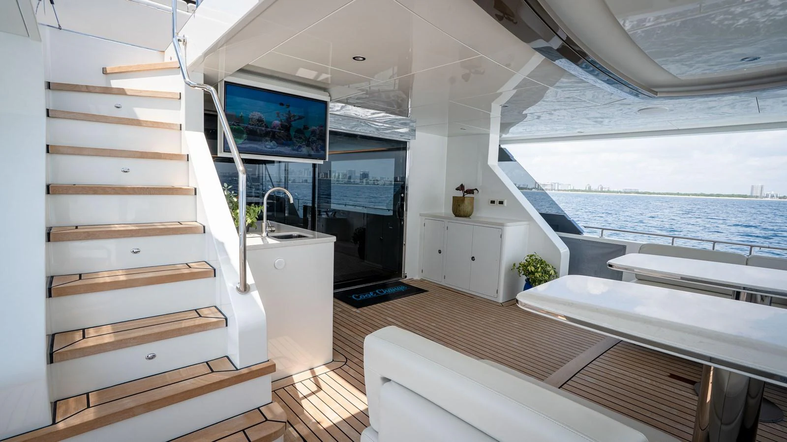 The aft deck features a comfortable seating area with a view of the water, complemented by a staircase leading to the upper deck. aboard COOL CHANGE Yacht for Sale