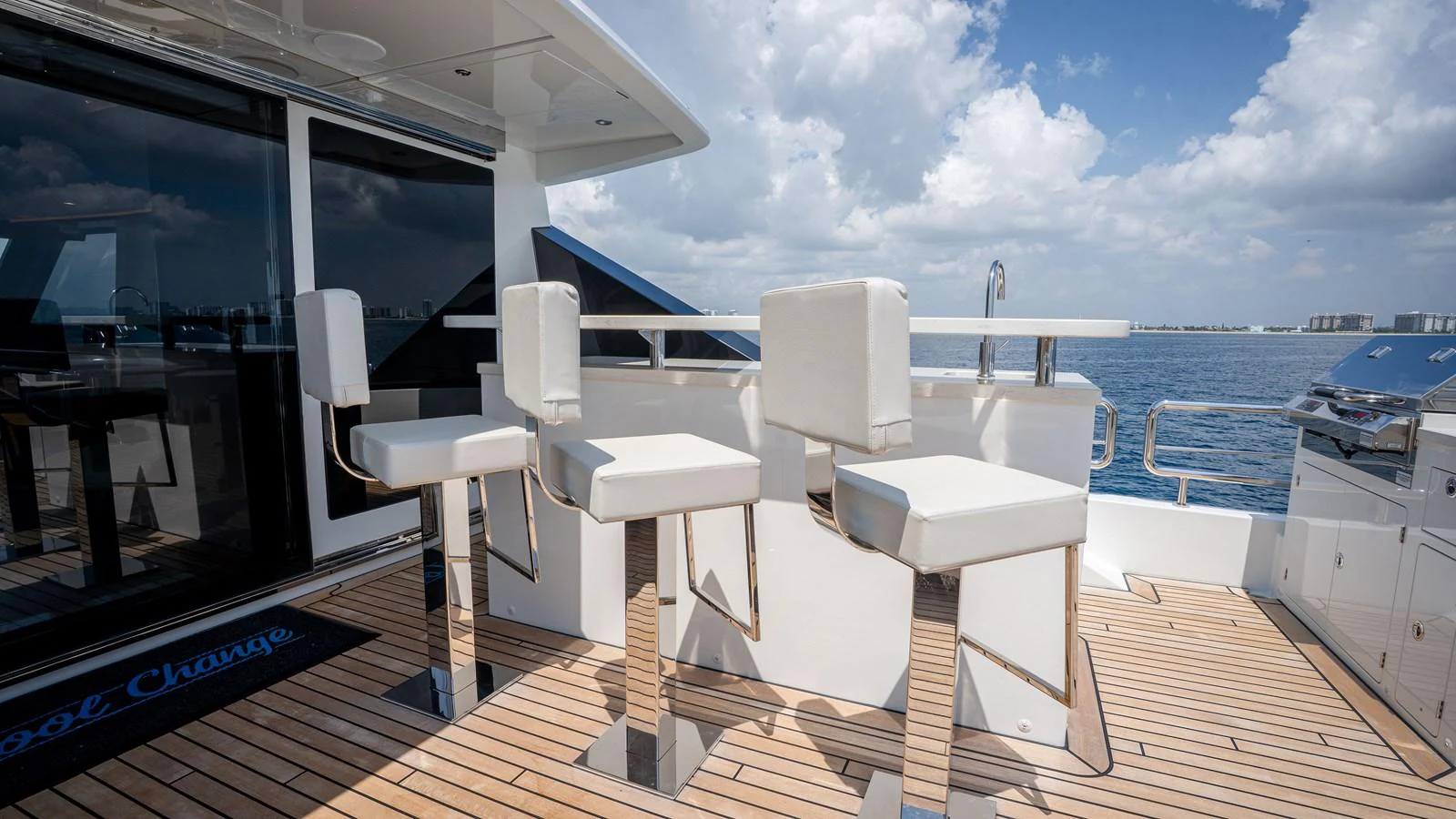 The aft deck features a stylish bar area with modern white bar stools and a sleek countertop, perfect for enjoying the ocean views. aboard COOL CHANGE Yacht for Sale
