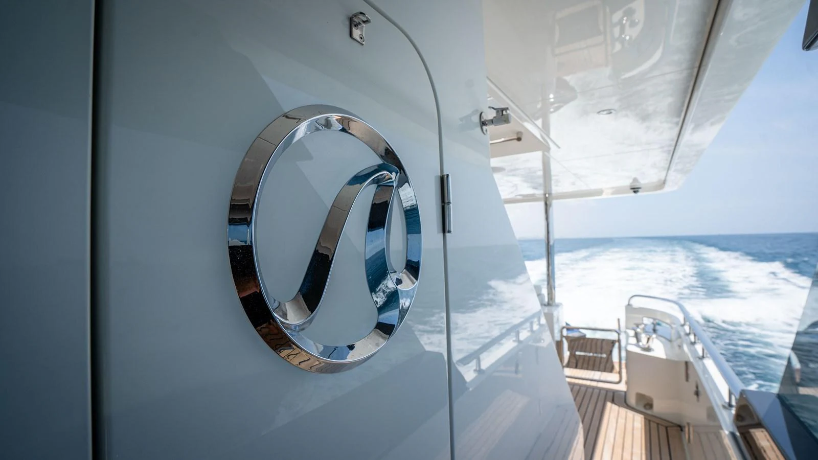 A close-up of a yacht's exterior detail with a sleek logo and a view of the sea in the background. aboard COOL CHANGE Yacht for Sale