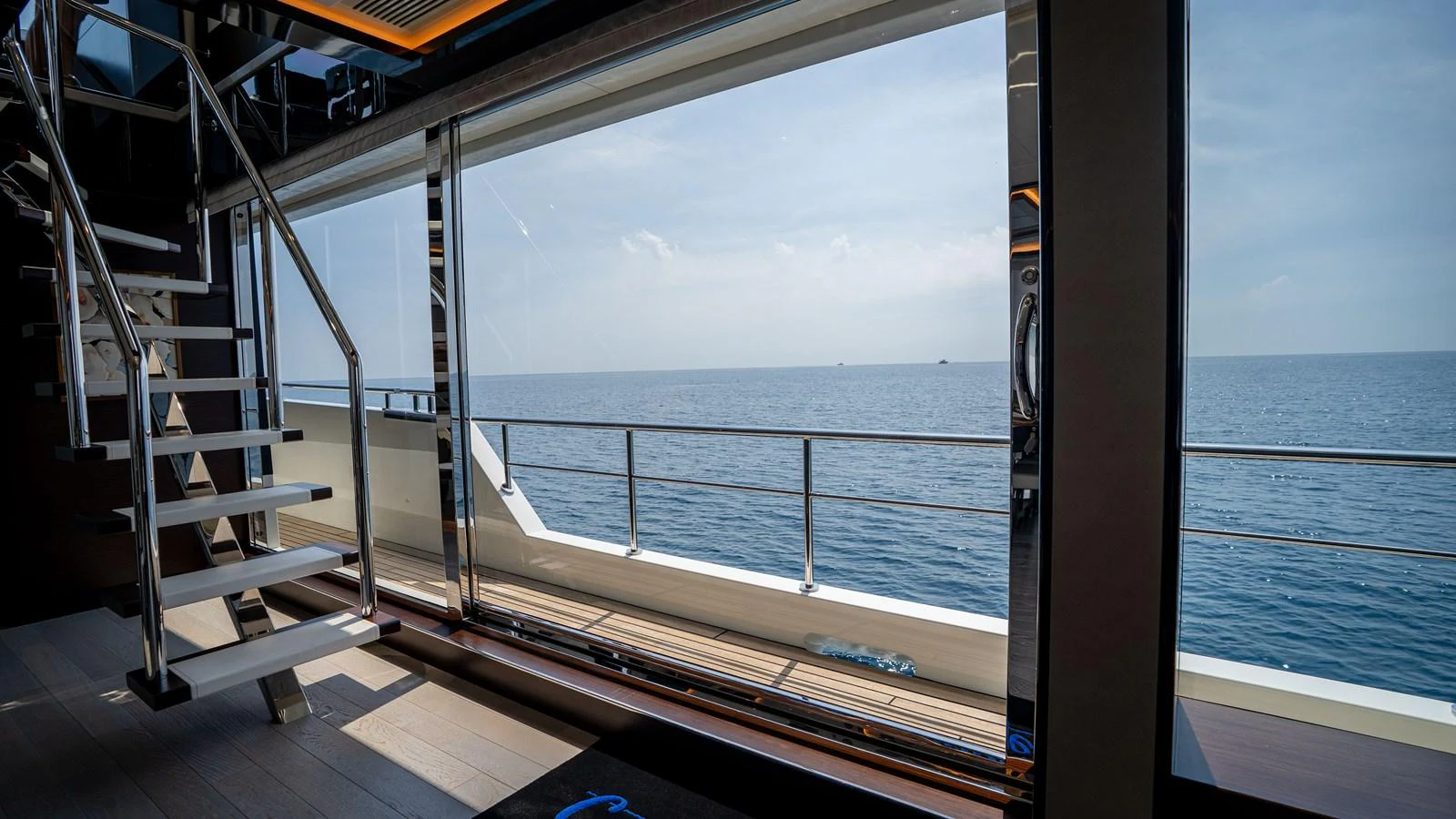 The interior of the yacht features a modern staircase and large windows offering a stunning ocean view. aboard COOL CHANGE Yacht for Sale