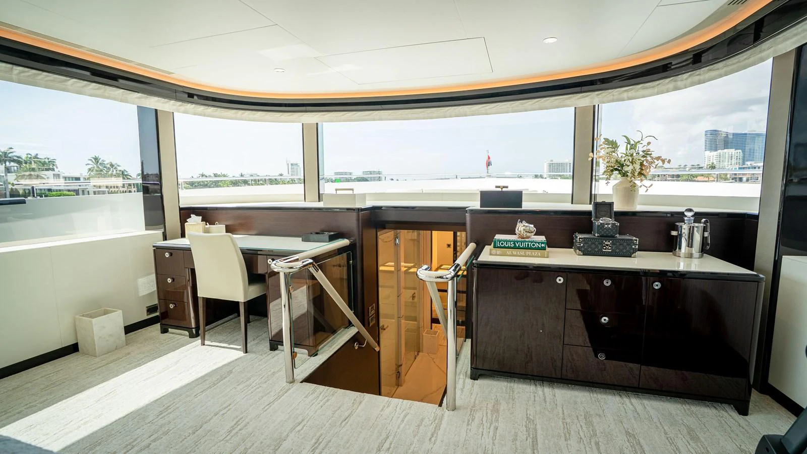 A luxurious interior space with a desk, seating area, and large windows offering a panoramic view. aboard COOL CHANGE Yacht for Sale
