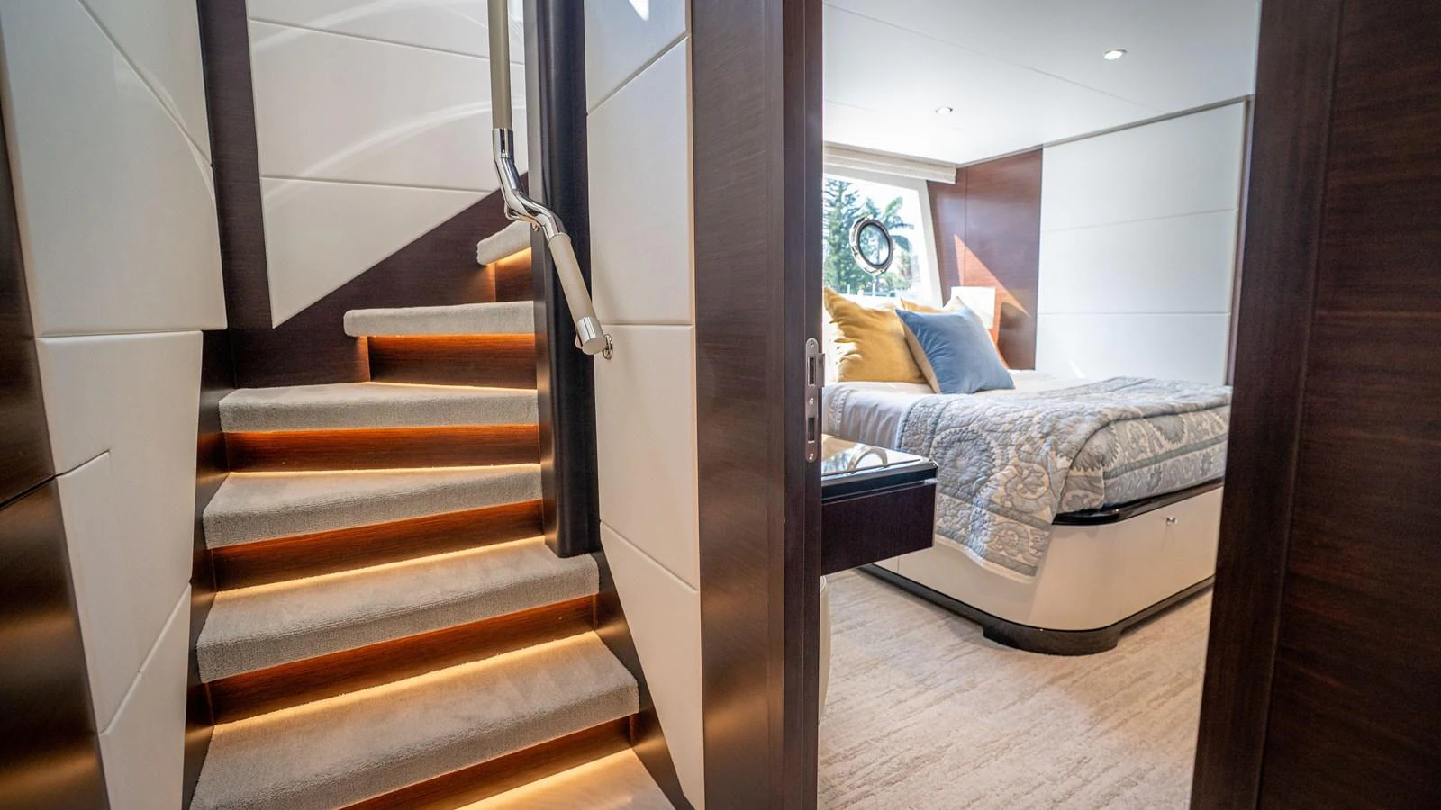 The image showcases a luxurious stateroom with a cozy bed and elegant staircase. aboard COOL CHANGE Yacht for Sale