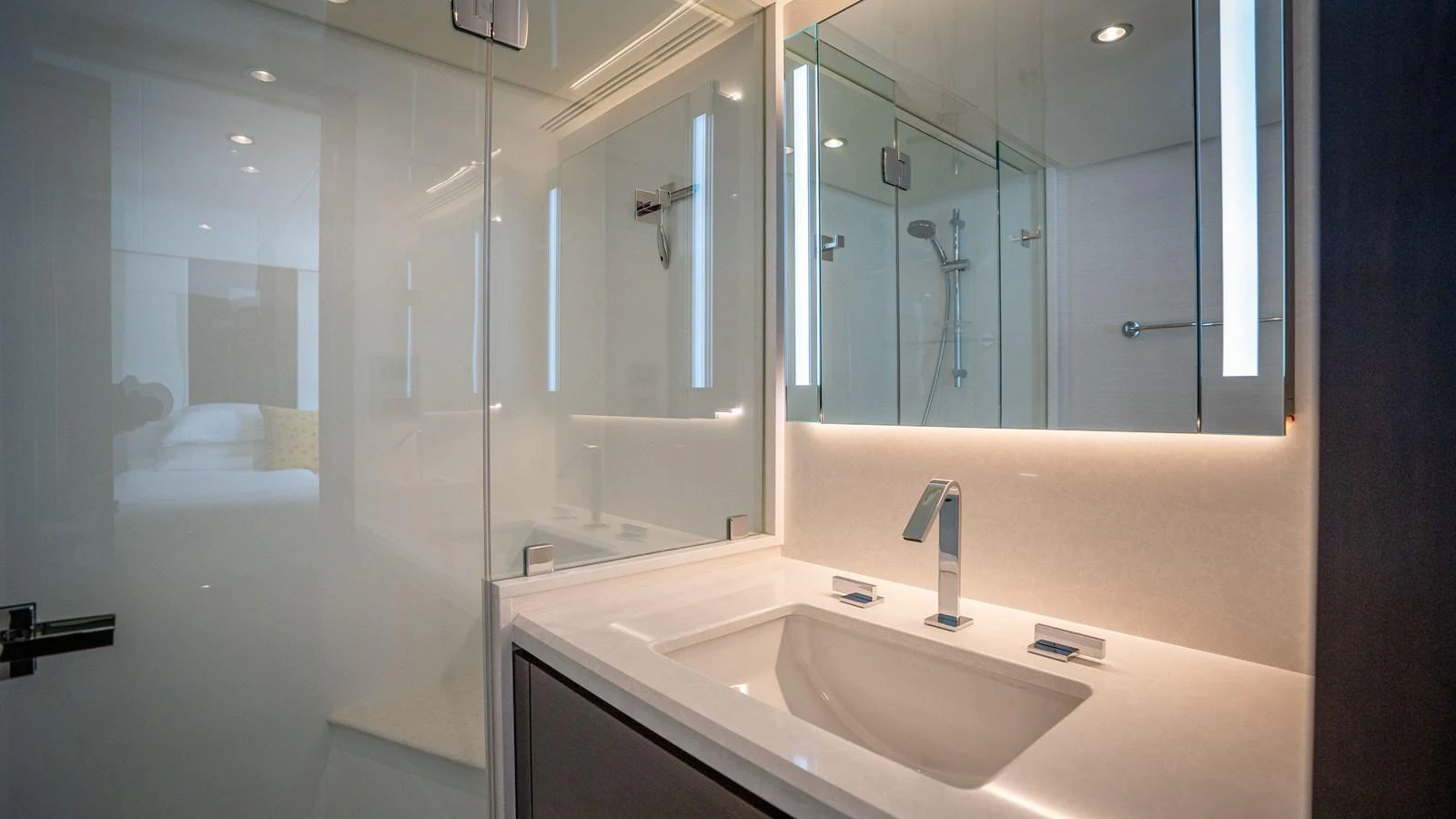 A sleek and modern yacht bathroom with a well-lit vanity and glass-enclosed shower. aboard COOL CHANGE Yacht for Sale