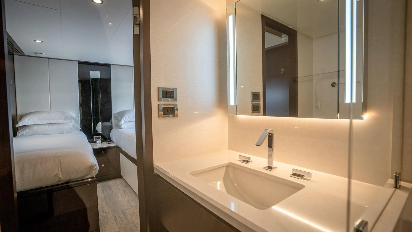 The yacht's bathroom features a sleek, modern design with a well-lit vanity and a view into the adjacent stateroom. aboard COOL CHANGE Yacht for Sale