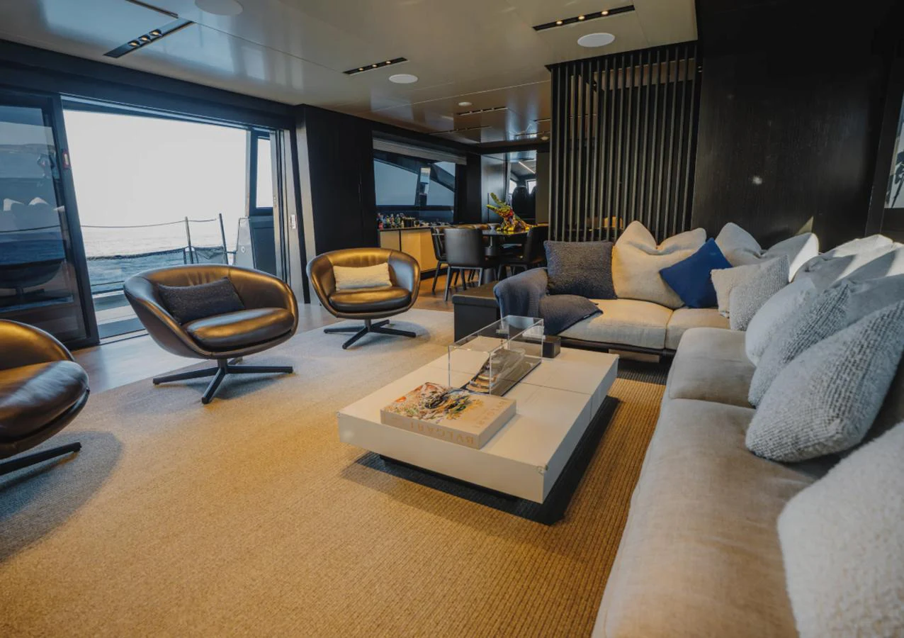 The salon features modern furnishings with a comfortable seating arrangement and a view of the sea. aboard BYEEE... Yacht for Sale