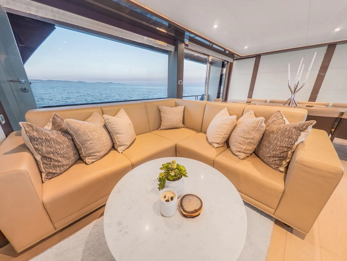 The salon features a plush L-shaped sofa with a stunning ocean view through large windows. aboard LONE STAR Yacht for Sale