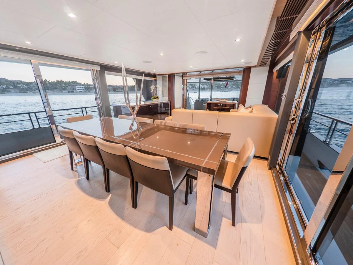 The yacht's dining area features a sleek table with comfortable seating, surrounded by large windows offering stunning water views. aboard LONE STAR Yacht for Sale