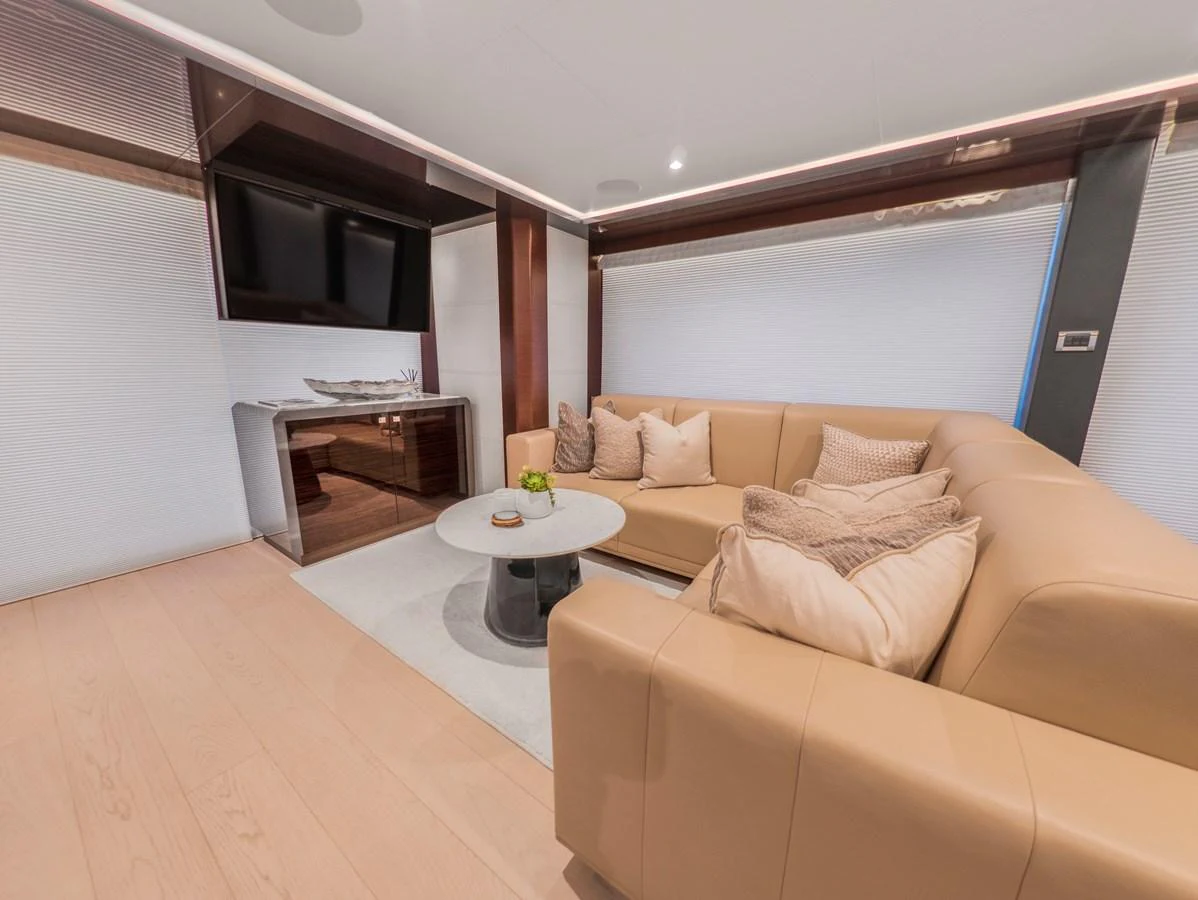 The salon features a comfortable beige sectional sofa and a sleek entertainment center. aboard LONE STAR Yacht for Sale
