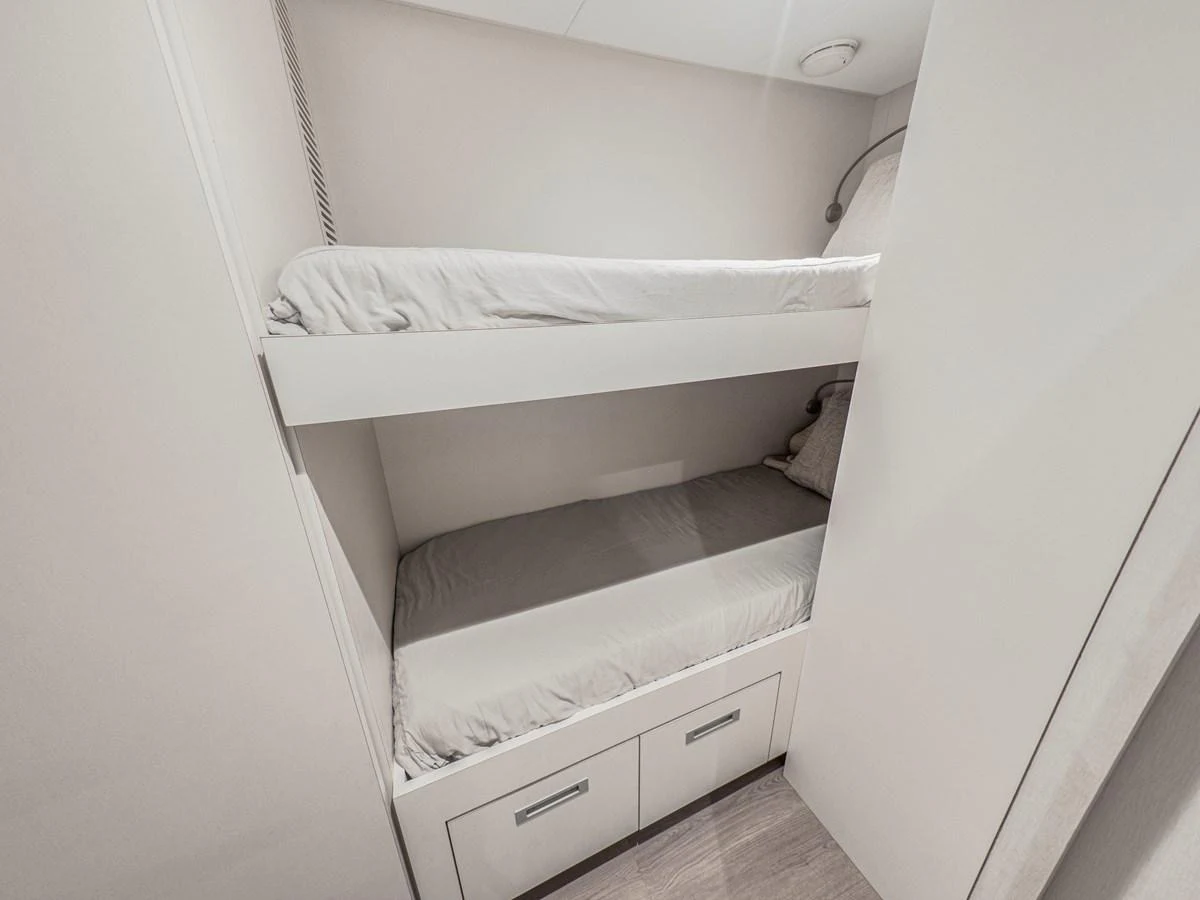 The image shows a compact and neatly arranged crew cabin with bunk beds and storage drawers. aboard LONE STAR Yacht for Sale