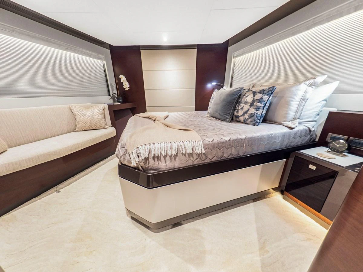 The stateroom features a luxurious bed with plush pillows and a cozy blanket, complemented by a comfortable seating area. aboard LONE STAR Yacht for Sale