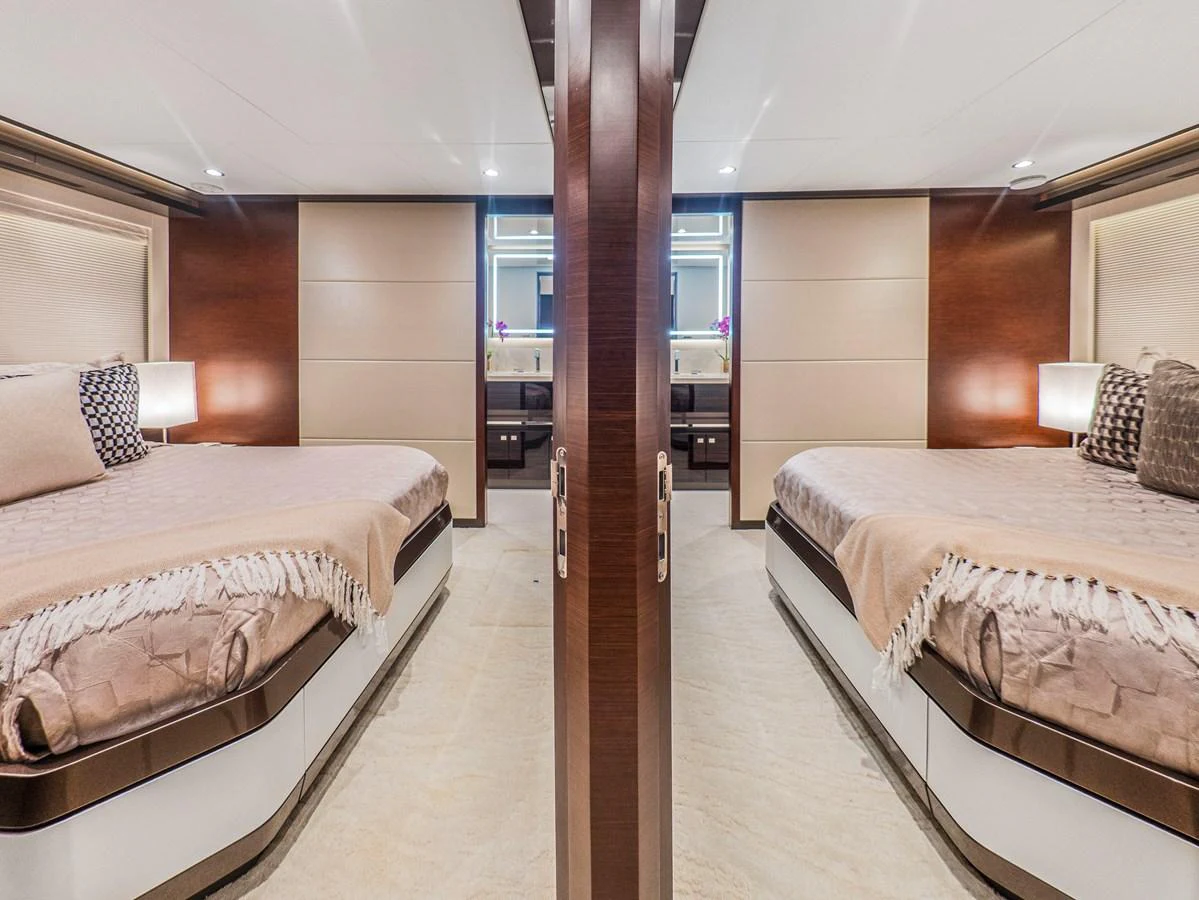 The guest stateroom features twin beds with elegant bedding and warm wood accents. aboard LONE STAR Yacht for Sale