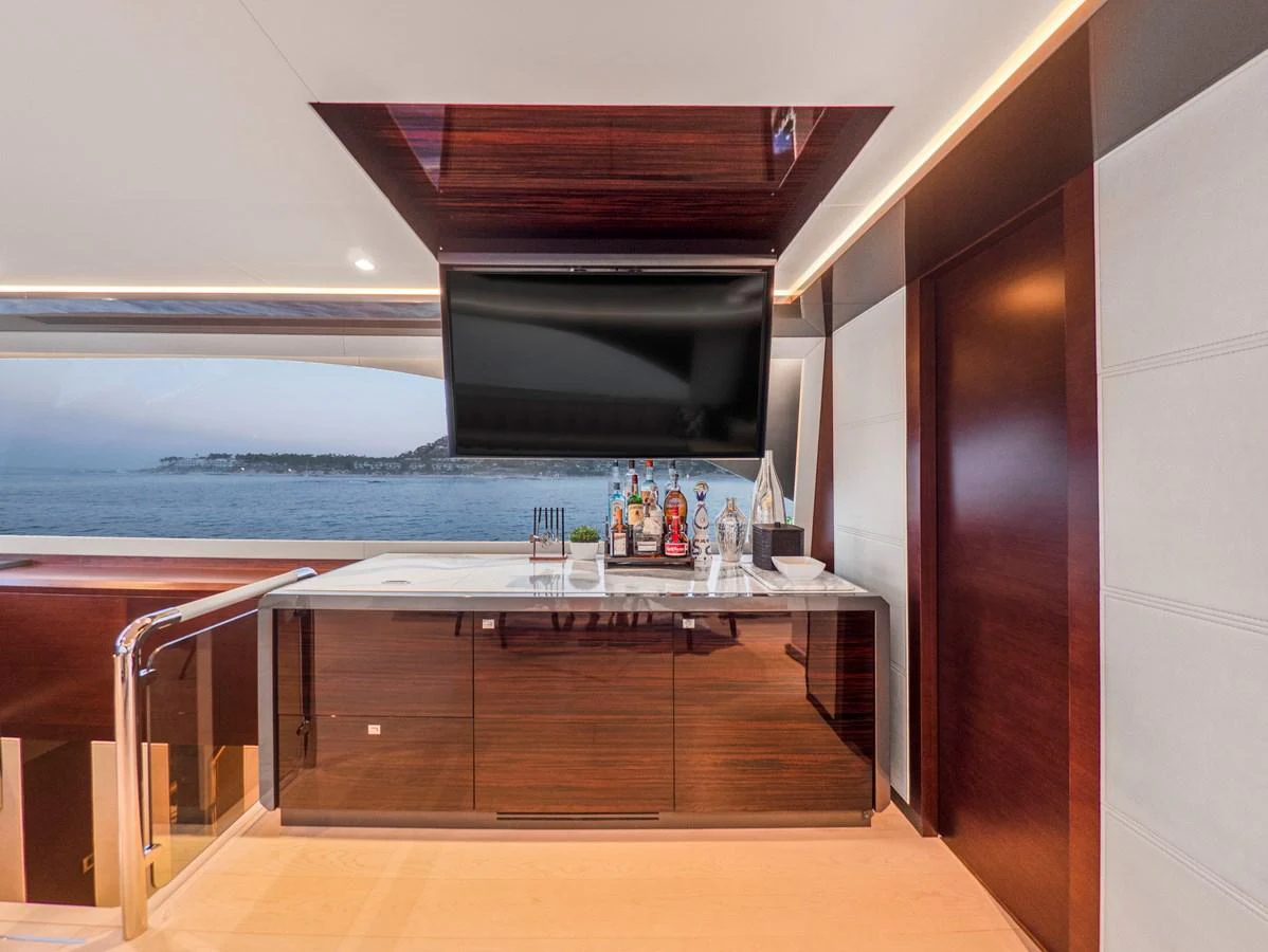 A stylish yacht interior featuring a well-equipped bar area with a flat-screen TV and a scenic ocean view. aboard LONE STAR Yacht for Sale