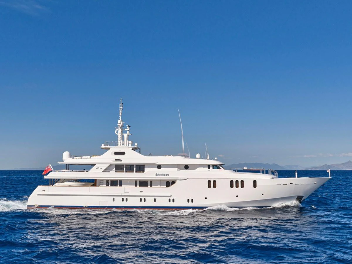 A stunning white yacht cruises gracefully on the open sea under a clear blue sky. aboard SAHAB IV Yacht for Sale
