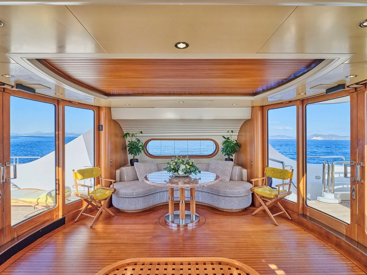 The salon features a cozy seating area with panoramic ocean views and elegant wooden finishes. aboard SAHAB IV Yacht for Sale