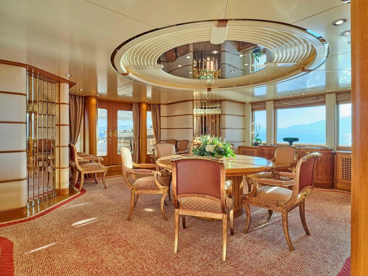The yacht's dining area features elegant wooden furniture and large windows offering stunning sea views. aboard SAHAB IV Yacht for Sale