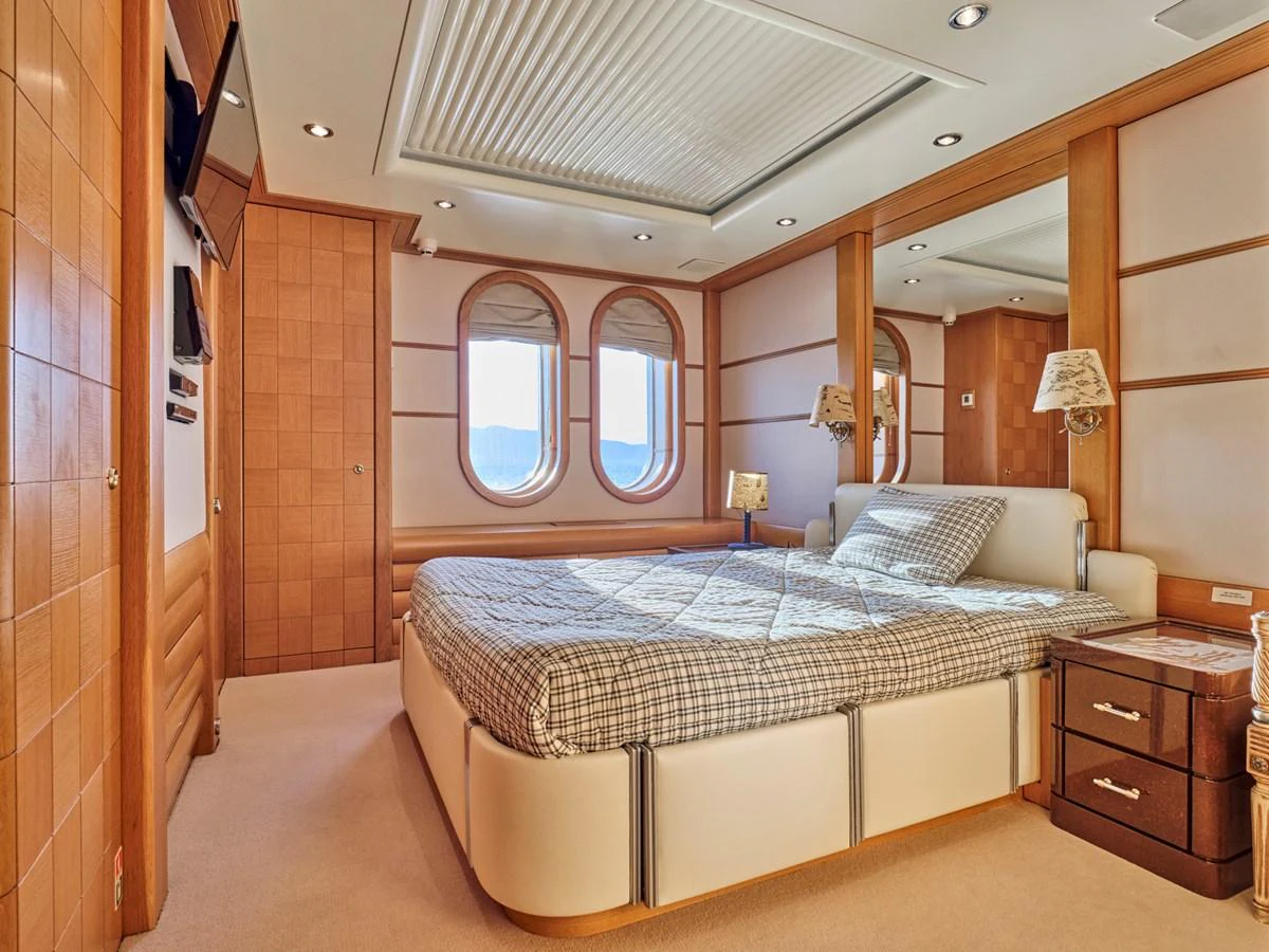 The master stateroom features a spacious bed, warm wood paneling, and large windows for natural light. aboard SAHAB IV Yacht for Sale