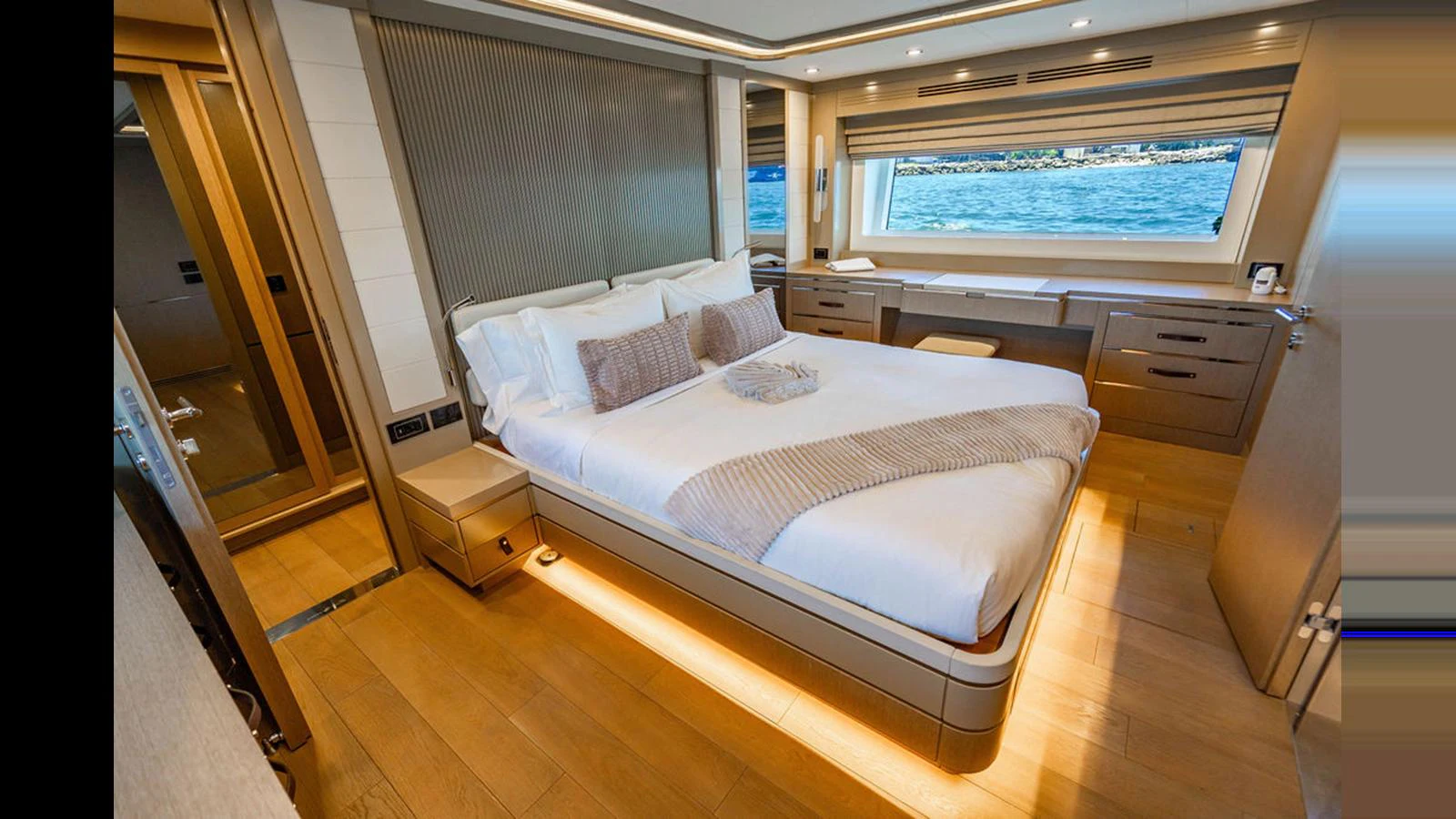 The master stateroom features a luxurious bed with a scenic view through a large window. aboard NIVASA Yacht for Sale