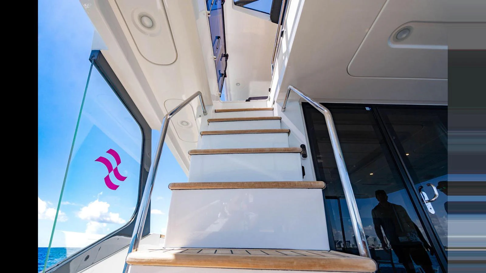 A sleek staircase with wooden steps leads to the upper deck, showcasing modern design elements. aboard NIVASA Yacht for Sale