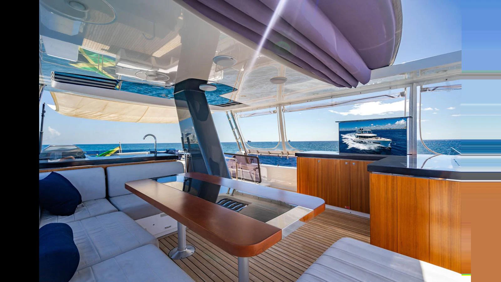 The aft deck features a comfortable seating area with a sleek dining table and a view of the open sea. aboard NIVASA Yacht for Sale